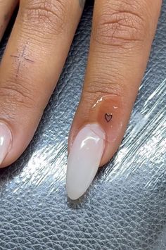 a woman's hand with white and pink nail polish on her nails, which has a heart drawn on it