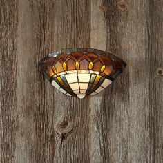 a stained glass light hanging on a wooden wall