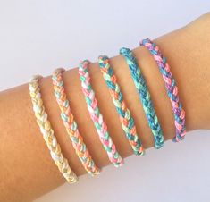 four different colored braid bracelets on a woman's arm, each with an individual's name