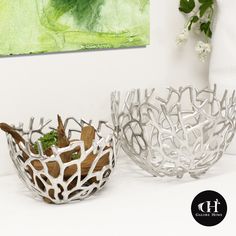 two white bowls sitting on top of a table next to a vase with flowers in it