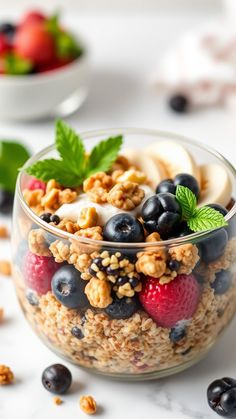 a glass bowl filled with granola and berries