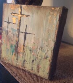 an old box sitting on top of a table with a cross painted on the side