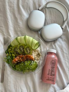 a bowl with rice, cucumbers, and salmon on it next to earbuds