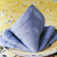 three folded napkins sitting on top of a white and blue plate with gold cloth