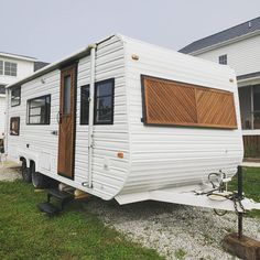 a white trailer parked on top of a green grass covered field next to a house