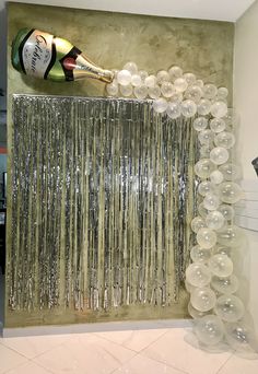 a bottle of champagne is being poured into the air in front of a curtain made out of balloons