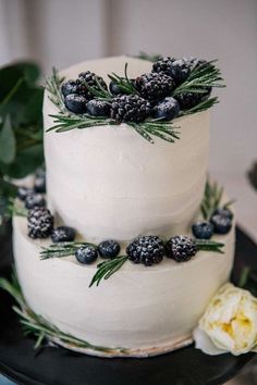 a white cake topped with berries and greenery