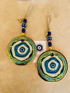 two blue and yellow earrings with beads hanging from the earwires on a marble surface