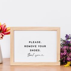 a wooden frame sitting on top of a table next to flowers