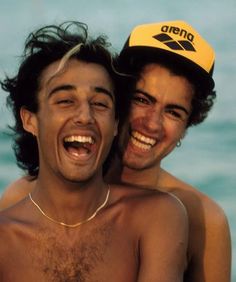 two young men are laughing together on the beach