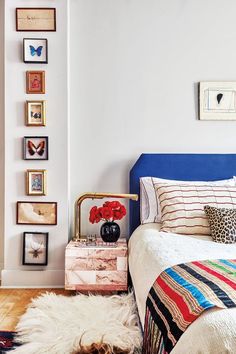 a bedroom with white walls and pictures on the wall above the bed, along with an animal rug