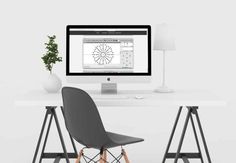 a desktop computer sitting on top of a white desk next to a chair and potted plant