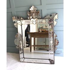 a mirror sitting on top of a wooden floor next to a table and chair in front of a blue wall