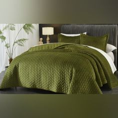 a bed with green bedspread and pillows