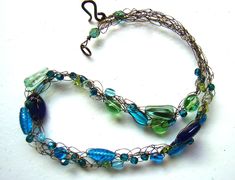 "This crochet wire necklace features beautiful Czech glass beads in a variety of shapes and sizes - all in shades of green, blue and teal. The beads are woven on bronze tone hypoallergenic wire and the necklace is finished with an easy to use artisan-made copper patina clasp. ElephantBeads crochet wire jewelry works well whether you're dressed up or dressed down in casual denim. Each piece can be gently manipulated to drape just right, and they are feather-light against the skin. Length: 17 inch Green Glass Wire Wrapped Necklaces, Green Glass Wire Wrapped Necklace, Green Wire Wrapped Czech Glass Beaded Necklaces, Green Wire Wrapped Beaded Necklace With Czech Glass, Green Wire Wrapped Czech Glass Necklace, Crochet Wire Jewelry, Wire Crochet Necklace, Teal Crochet, Crochet Wire