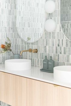 a bathroom with two sinks and a round mirror on the wall above it's counter