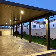 an outdoor covered patio area with lights on the ceiling and grass in the back yard