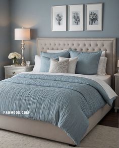 a bedroom with blue and white bedding, two pictures on the wall above it