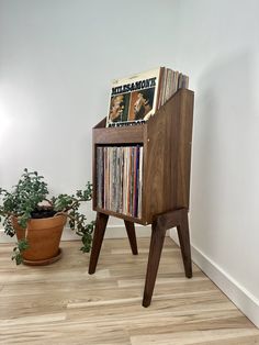 an old record player stands in front of a potted plant on the wooden floor