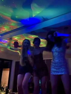 three young women are dancing in a room with colorful lights on the ceiling and floor