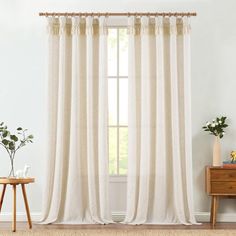 a living room with white curtains and a wooden table in front of the window on top of a rug