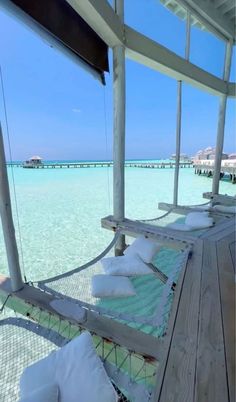 a hammock on the deck of a boat in clear blue water with white pillows