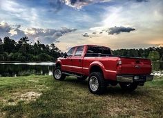 a red pick up truck parked next to a lake