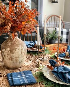 the table is set with plates, napkins and flowers in a vase on it