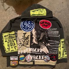 a jacket with various stickers on it sitting on top of a cement floor next to a wall