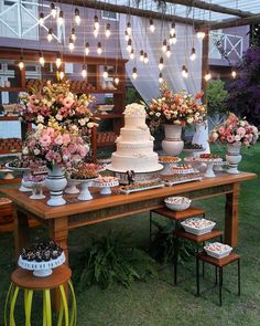 a table topped with lots of cakes and desserts next to tall vases filled with flowers