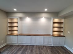 an empty room with built in bookshelves and wood flooring on the walls