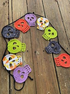 crocheted sugar skulls are arranged in a circle on a wooden surface with string