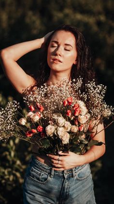 a woman holding a bouquet of flowers in her hands and looking up at the sky