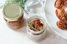 three jars filled with food sitting on top of a white table next to a plate