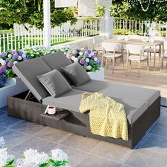 an outdoor daybed with pillows and blankets on it in front of a patio area