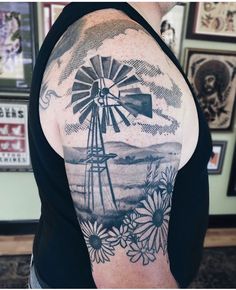 the back of a woman's shoulder with a windmill tattoo on her left arm