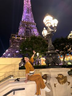 a woman sitting on a bench in front of the eiffel tower at night