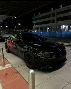 a black car parked on the side of a road next to a parking meter at night