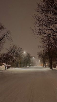 a snow covered street at night with no cars on it