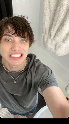 a young man taking a selfie in the bathroom with his hand up to his face