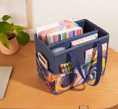 an open bag sitting on top of a wooden table next to a laptop and potted plant