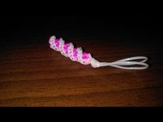 a toothbrush with pink and white beads on it sitting on a wooden table in the dark