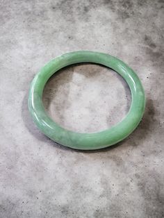 Our 'Earth's' Bangle Bracelets are all one-of-one pieces; This piece is famed for its unique green and white hues with fantastic translucency and optics. The marbling effect creates a depth and tone of hue and pattern, displaying brilliance and scintillation like no other. This piece has no cracks, blemishes, or scratches. With the most sought after fibrous, cloud-like granular patterns and marbling of hues. These structures are like signatures, distinctly identifying each bracelet as truly unique.  Handpicked from the best parts of a Burmese Jadeite Rough stone. The Burmese A-Jadeite is completely untreated, un-enhanced. Certification available upon request for an additional cost.  Perfect to wear on Formal or Casual wear alike. This unisex bracelet has a rich appearance. Ref: A1EBJBB0880 Modern Green Bangle Jewelry, Modern Green Bangle, Classic Green Bangle Jewelry, Classic Green Round Bangle, Classic Green Bangle Bracelet, Jade Bangle, Unisex Bracelets, Burmese, Jade