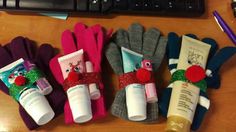 four gloves are lined up next to each other on a desk, with toothbrushes and lotion in them