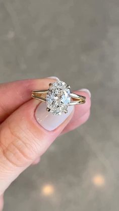 a woman's hand holding an engagement ring with two diamonds on it and the other side