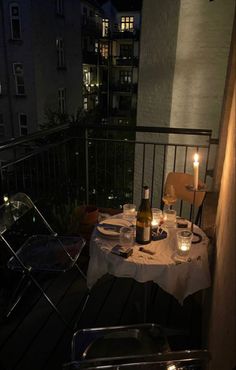 a table with two bottles of wine on top of it next to a balcony at night