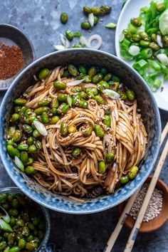 a bowl filled with noodles, peas and sesame seeds