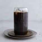 a glass filled with liquid sitting on top of a plate