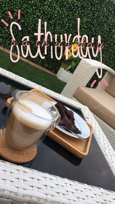 a cup of coffee sitting on top of a table next to a plate with cake