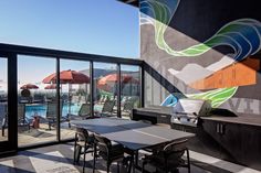 an outdoor patio with tables, chairs and umbrellas next to a swimming pool area